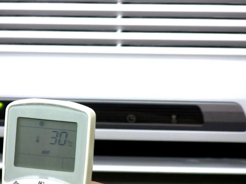 osoba podešava klimu sa daljinskim upravljačem